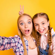 Childish playful mood concept! Close up photo portrait of funny funky comedian joyful carefree shocked surprised with open mouth and showing two fingers behind head girls isolated bright background